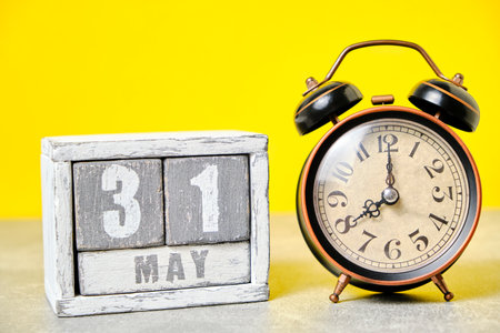 May 31 on a wooden calendar and an old retro alarm clock on a yellow backgroundの写真素材