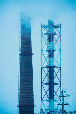 Two industrial pipes smoke polluting the environment with harmful gasesの写真素材