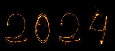 Year 2024 is written in numbers black background with sparklers with sparksの写真素材