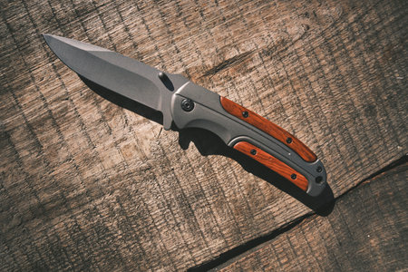 Folding tactical knife lies wooden table topの写真素材