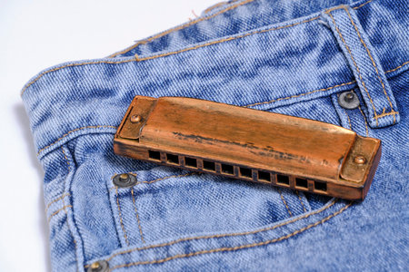 Harmonica, musical instrument, lies on denim pantsの写真素材