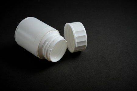 Empty medicine jar with an open lid black backgroundの写真素材