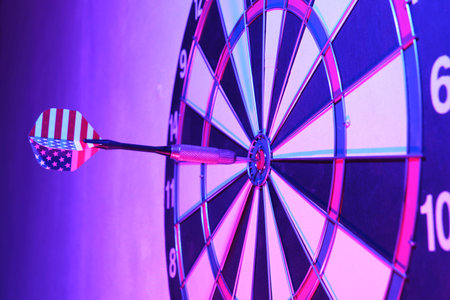 Dartboard and dart are stuck in center of board.Bright rainbow photoの写真素材