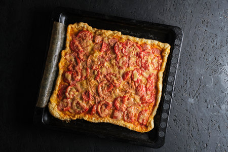 Pizza with tomatoes, sausage and cheese in baking dishの写真素材