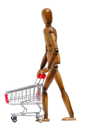 Wooden brown mannequin rolls shopping cart in front him.Concept going to the storeの写真素材