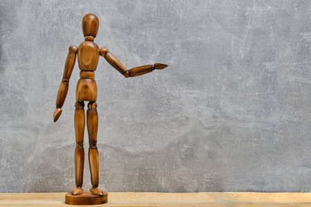 Wooden mannequin stands with an outstretched arm gray background.Concept offering and beggingの写真素材