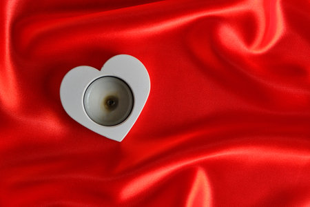 White candle holder shape heart background red silk fabricの写真素材