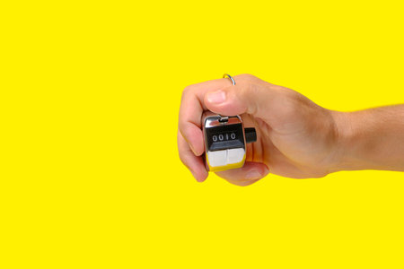 Manual mechanical counter in hand on yellow backgroundの写真素材