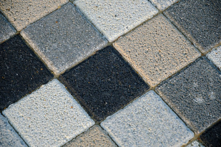 Checkered mosaic, multicolored paving slabs in closeup in gray and beige tones