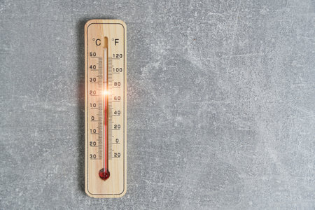 Thermometer showing high temperature.Against background concrete wallの写真素材