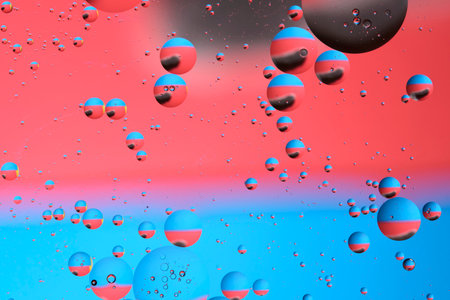 Macro photography with circles oil droplets water surface. Abstract with blue, black and red background with oil bubblesの写真素材