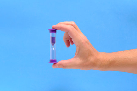 Hand blue background holds an hourglassの写真素材