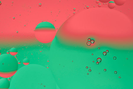 Macro photo with circles oil droplets water surface. Abstract green and red background with oil...