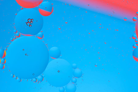 Macro photo with circles oil droplets water surface. Abstract blue and red background with oil...