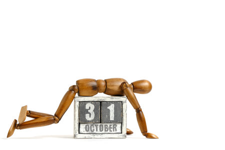 October 31, wooden calendar with mannequin lying on it on white background. Calendar date