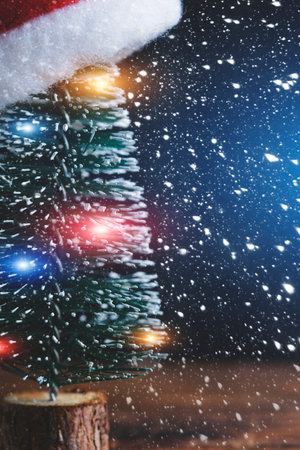 Christmas tree with garland is decorated with Santa Claus hat background falling snowの写真素材