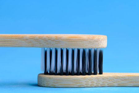 Eco friendly wooden toothbrushes with white and black bristles blue background