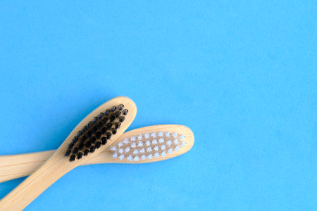 Eco friendly wooden toothbrushes with white and black bristles blue backgroundの写真素材