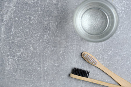 Glass of water and two wooden toothbrushes gray concrete background in bathroomの写真素材