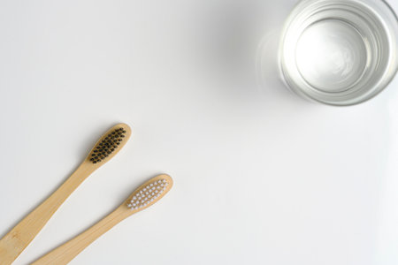 Glass water and two wooden toothbrushes bathroom on a white backgroundの写真素材