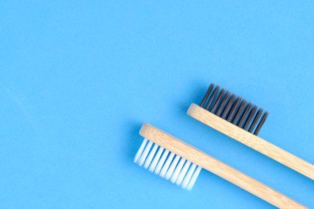 Eco friendly wooden toothbrushes with white and black bristles blue backgroundの写真素材