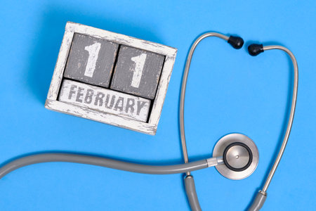 Date is February 11th on calendar and a stethoscope on blue background. World Sick Day.の写真素材
