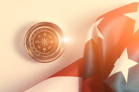 Compass pointing west and star spangled flag United States America