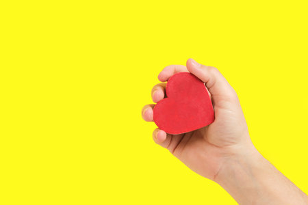 Heart in Hand Against Yellow Background. Evokes feelings of tenderness and sincerity, great for expressive visualsの写真素材
