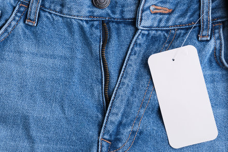 Denim pants with an unbuttoned fly and label hanging on themの写真素材