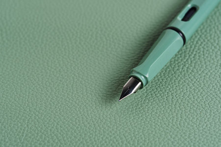 Green fountain pen lies green leather tabletop deskの写真素材