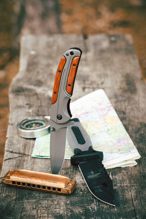 Knife with a harmonica and a map on a wooden background