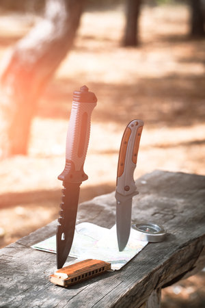 Knife and map on a wooden table in the forest. Travel concept