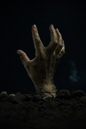 Zombie hand rising from the ground on black background. Halloween concept.