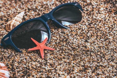 Blue sunglasses with starfish and seashells on the beach.の写真素材