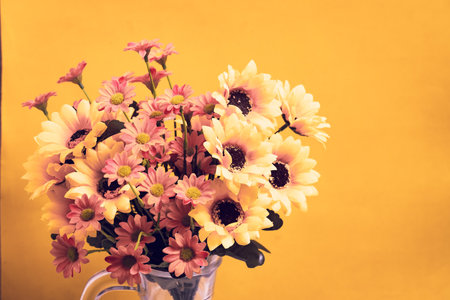 Vintage color of artificial flowers in vase on yellow background.の写真素材