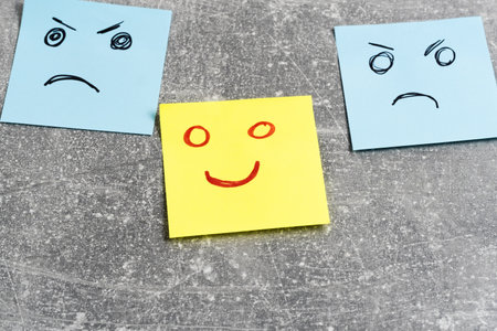 Emotional smiley faces on sticky notes on grey background, closeupの写真素材