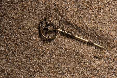 Old key on the sand. Vintage key on the sand background.の写真素材