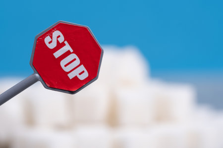 Stop sign on the background of white sugar cubes. The concept of stop eating sugar.の写真素材