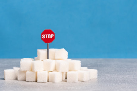Sugar cubes and red stop sign on table against blue background.の写真素材