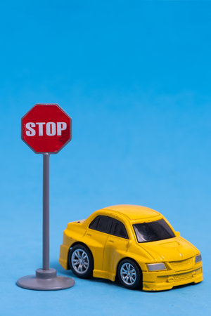 Toy car and stop sign on a blue background. The concept of stopping the car.