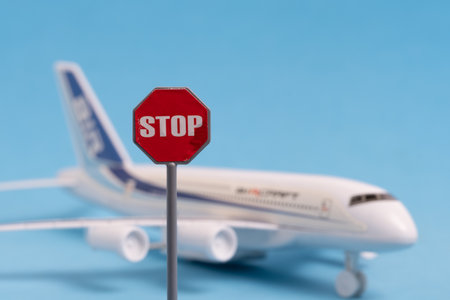 Stop sign on a blue background with a miniature model of a passenger plane