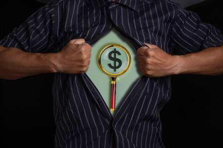Businessman with magnifying glass and dollar sign on his chest.の写真素材