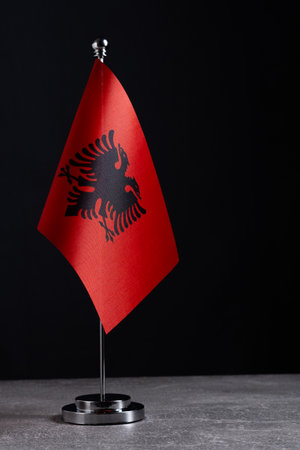 Albania flag on a stand against a dark background. National flag of Albaniaの写真素材