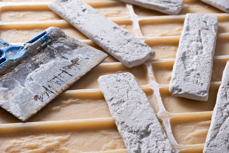 Closeup of a construction spatula and decorative bricks lying on silicone mold.