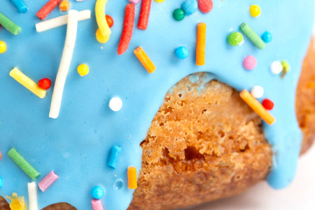 Cake with blue icing and colorful sprinkles on a white background