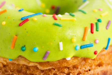 Green glazed donut with colorful sprinkles, close up.