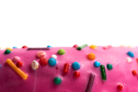 Close up of pink donut with sprinkles isolated on white backgroundの写真素材