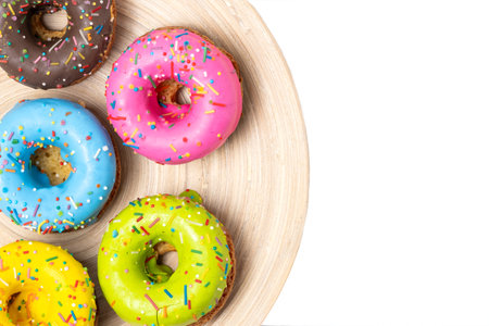 Colorful donuts on wooden plate isolated on white background. Top view.の写真素材