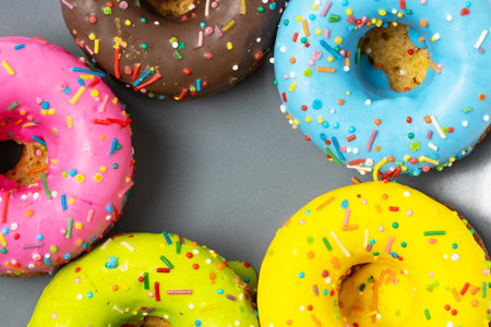 Colorful donuts with sprinkles on grey background, top viewの写真素材