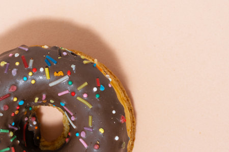Donut with chocolate icing and colorful sprinkles on brown background.の写真素材